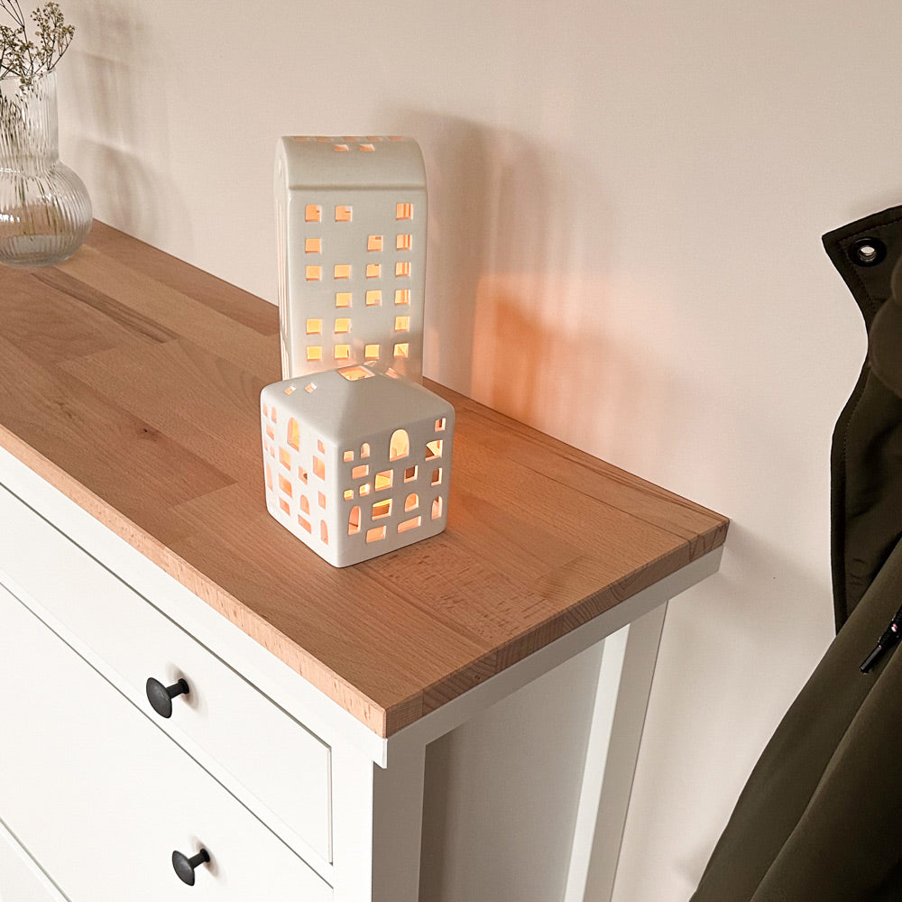 Seitliche Aufnahme von einer ungeölten Buchenholzplatte, die passgenau auf einem IKEA Hemnes Schuhschrank mit 2 Fächern liegt. Auf der Holzplatte sieht man noch Windlichter.