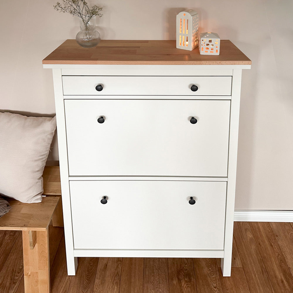 Frontalansicht von einem weißen IKEA Hemnes Schuhschrank mit 2 Fächern und einer Holzplatte aus Buchenholz oben drauf.