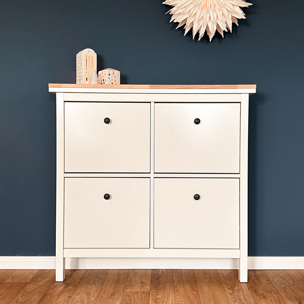 Weißer IKEA Hemnes Schuschrank mit 4 Fächern vor einer blauen Wand. Auf dem Schrank liegt eine ungeölte Holzplatte aus Buche.