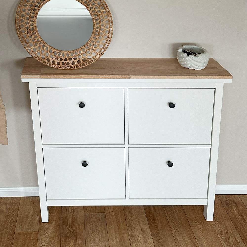 Weißer IKEA Schuhschrank Hemnes mit 4 Fächern. Auf dem Schrank liegt eine natur belassene Holzplatte aus Buche. Auf der Platte steht ein Spiegel und eine Deko-Schale.