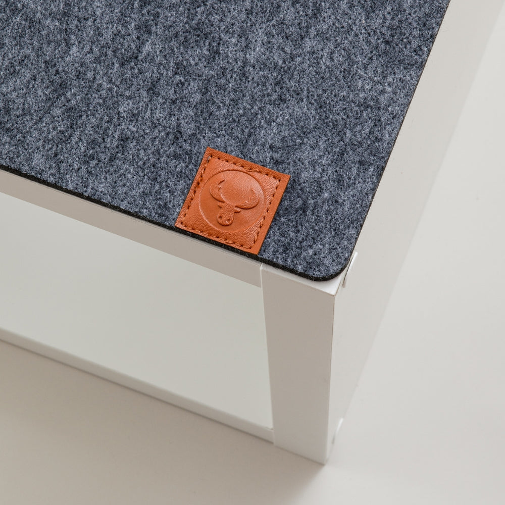 Detailaufnahme einer grauen Kallax Bankauflage aus Filz mit New Swedish Design Logo aus braunem Leder.