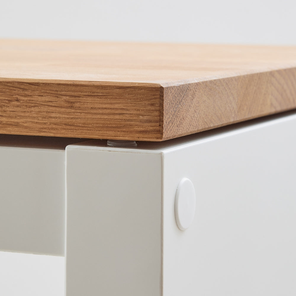 Detailaufnahme von einer Vollholzplatte aus geöltem Eichenholz, die auf einem Gummipuffer aufliegt, der auf ein IKEA Kallax Regal geklebt wurde.