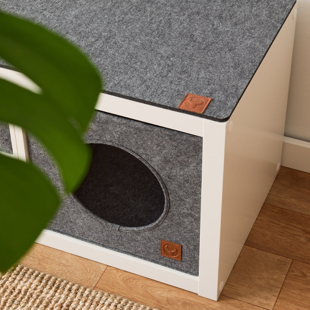 Weißes Kallax Regal mit grauer Katzenbox und Bankauflage aus Filz.
