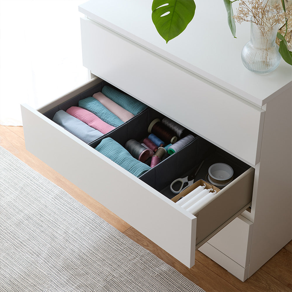 Eine offene Schublade in einer weißen Malm Kommode, die mit 3 bestückten Schubladenboxen gefüllt ist.