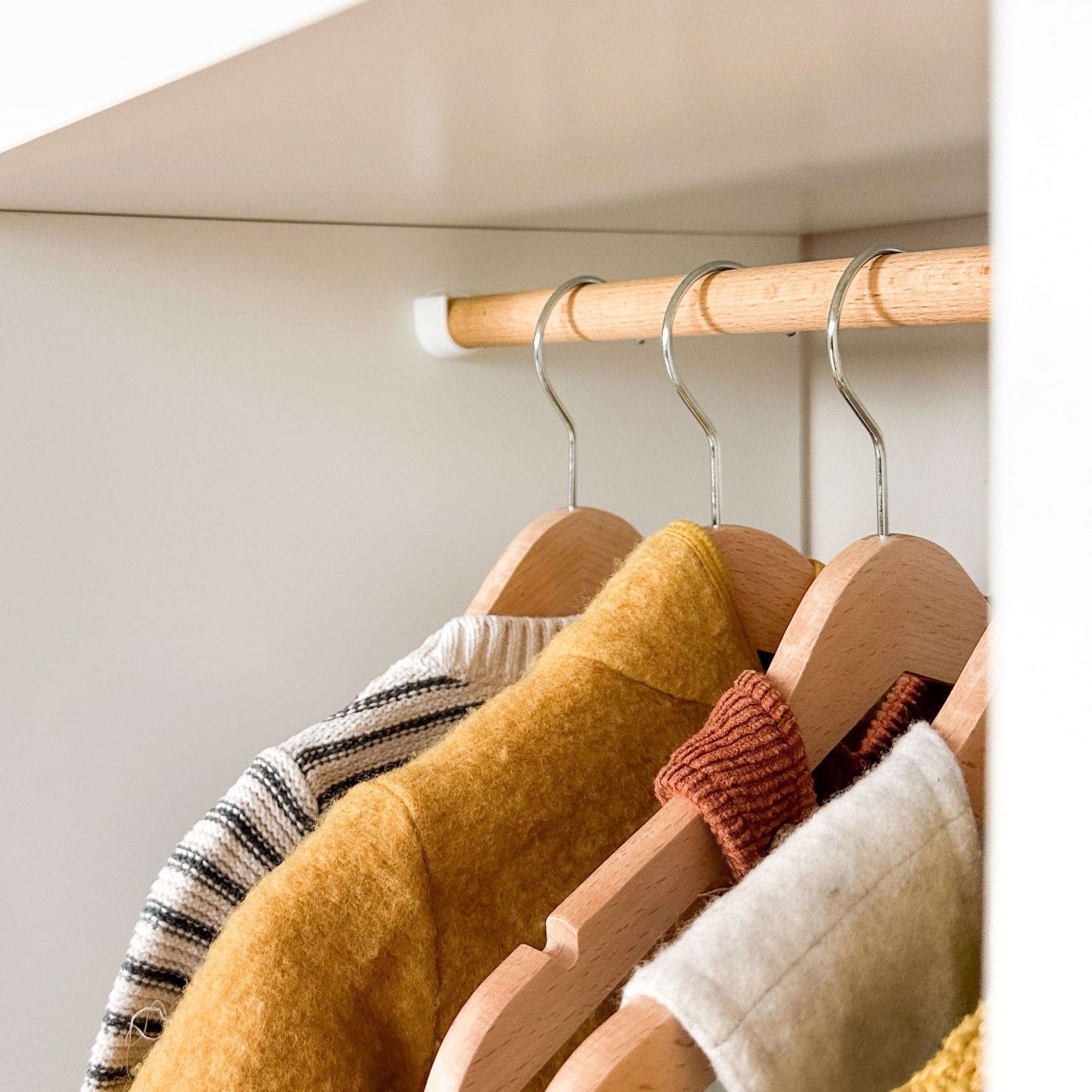 Kallax Kleiderstange mit auf Bügeln gehängter Kleidung für Kinder.