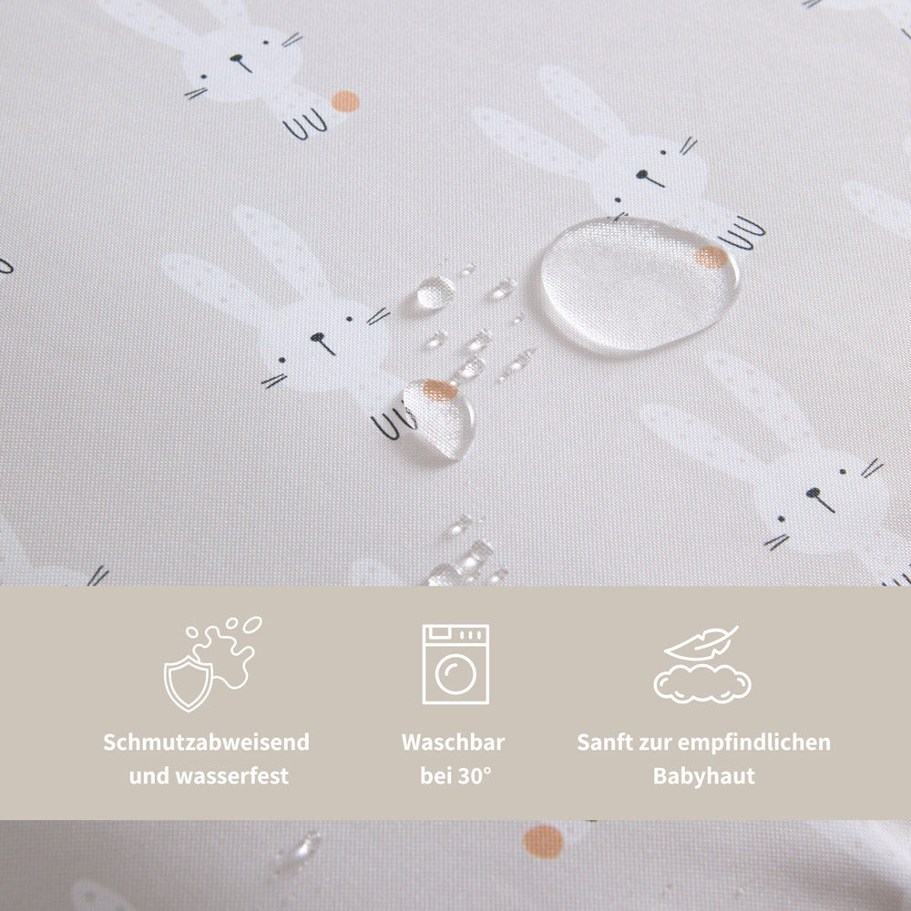 Nahaufnahme Wickelauflage beige mit Hasen, die zeigt, dass die Oberfläche feuchtigkeitsabweisend ist.