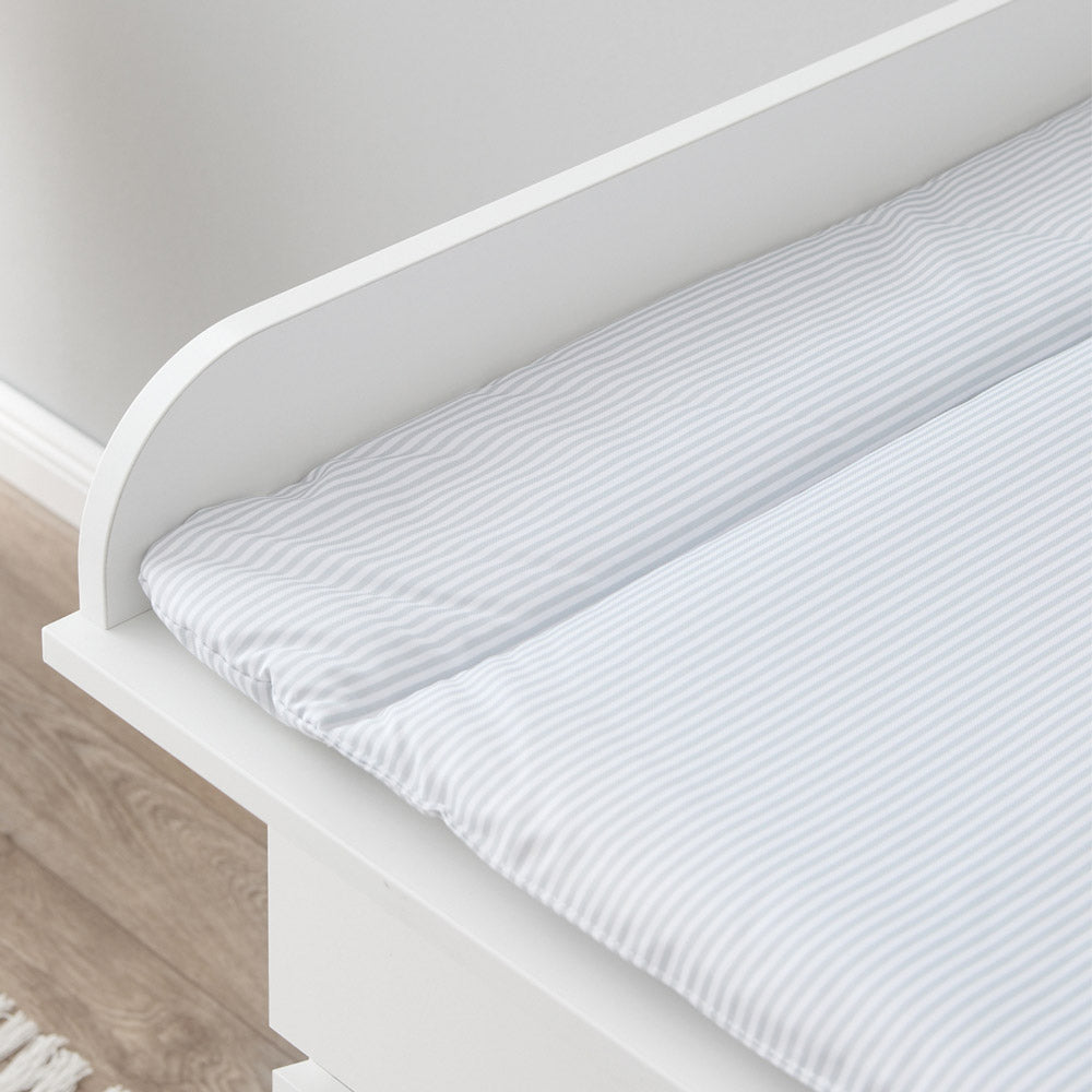 Detailaufnahme einer weißen Wickelauflage mit grauen Streifen auf einer Wickelkommode.